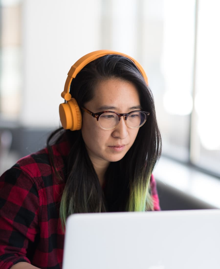 A tutor working at her laptop by a bright window